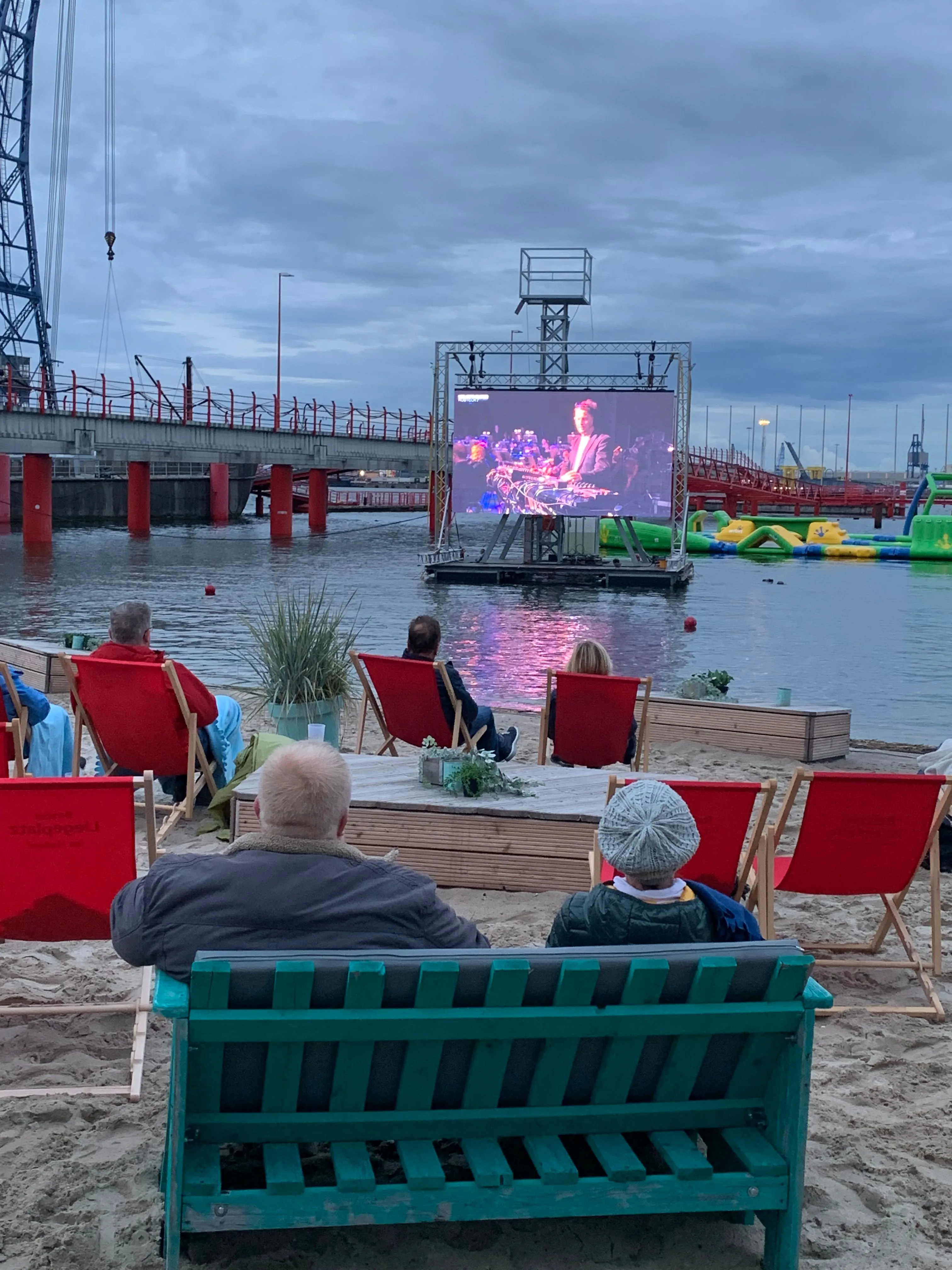 LED-Kinoleinwand auf dem Wasser mit Zuschauern am Strand